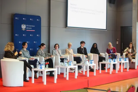 Panel międzynarodowy poświęcony strategiom promocji zdrowia psychicznego w erze cyfrowej. Uczestniczki i uczestnicy siedzą w półokręgu na scenie, na tle logotypu Ministerstwa Zdrowia oraz ekranu z tytułem sesji.